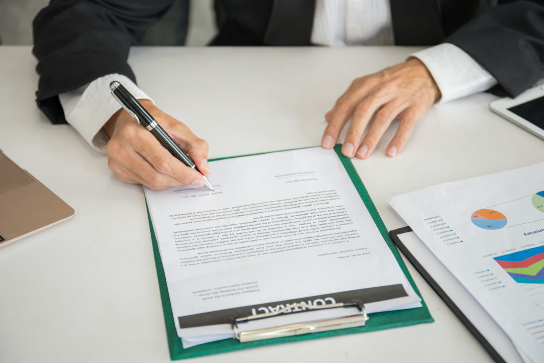 A close-up of hands signing a legal document.